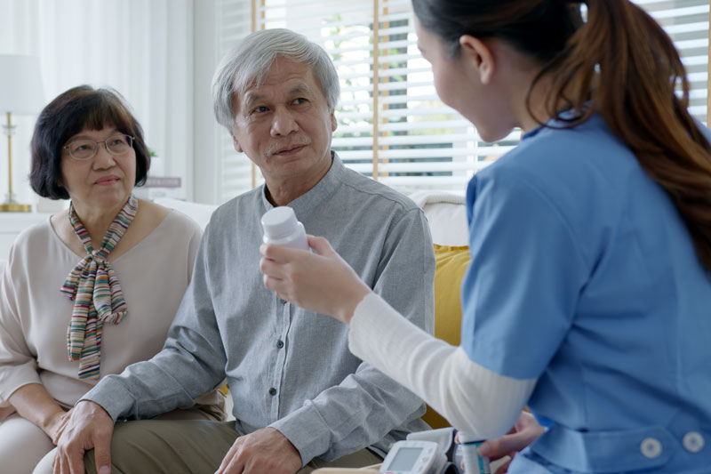 a nurse talks about medication with two elderly people
